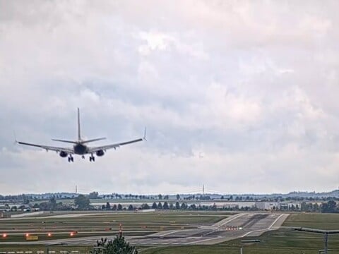 Airliner on final approach nose-on over the fields at Prague airport