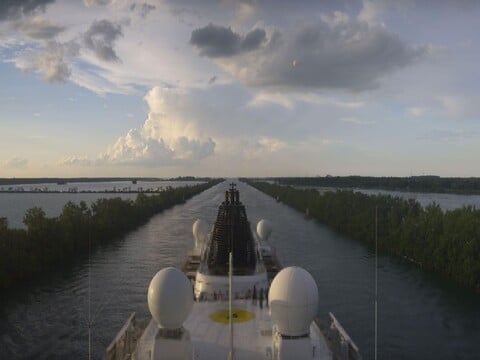 Viking Octantis sailing a narrow tree-lined channel with radar domes on the bow deck